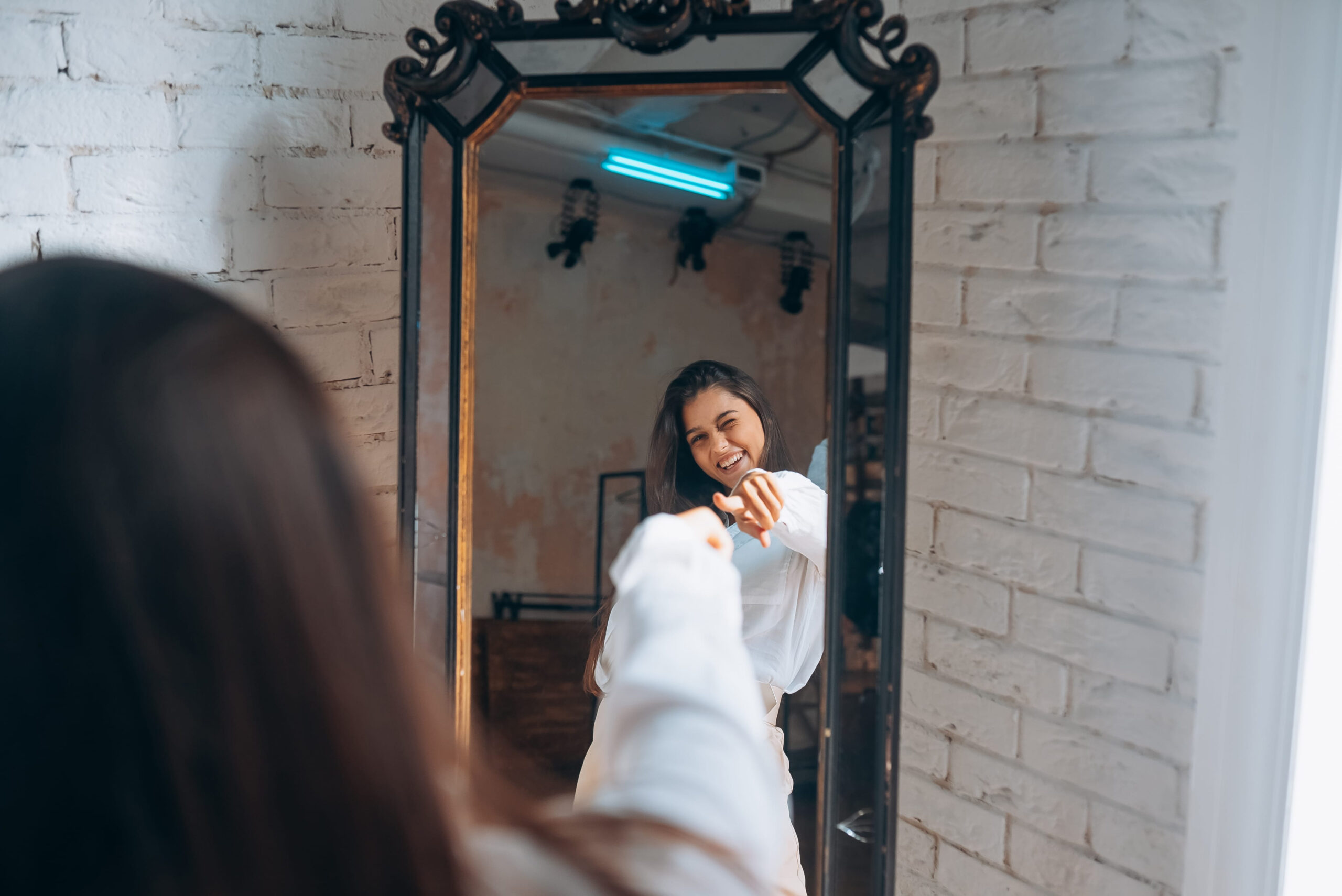 Young woman looks in the mirror. Reflection of a beautiful woman